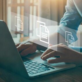 Frau an einem Notebook mit Icons für Dateien, die den Prozess der digitalen Dokumentation symbolisieren